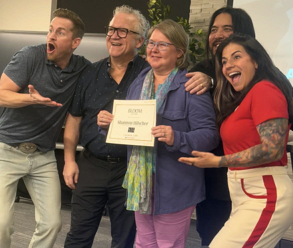 Five people celebrating with the person in the middle holding a certificate.